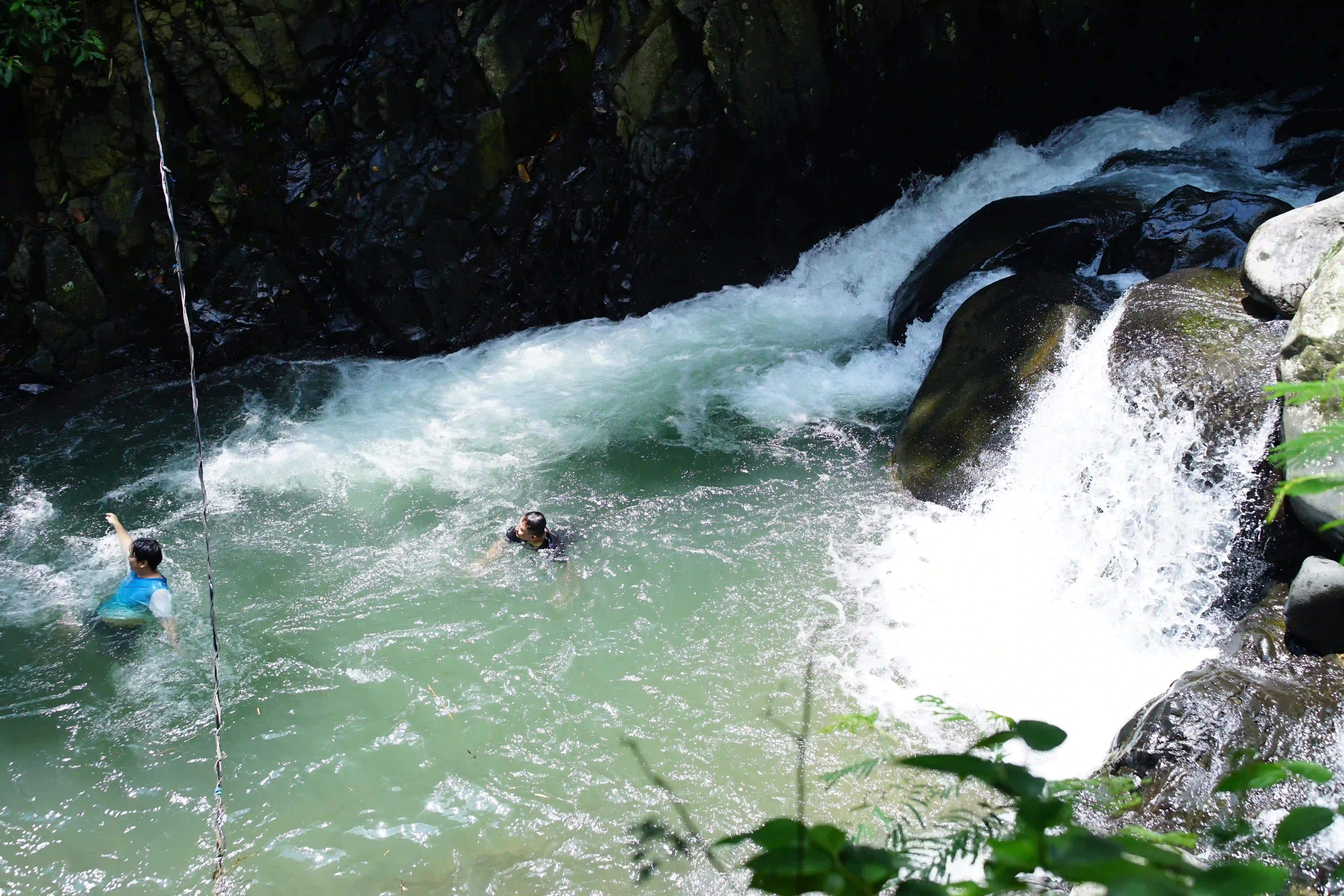 Dua peserta menikmati kesegaran air di kolam alami dekat bebatuan dan arus sungai.