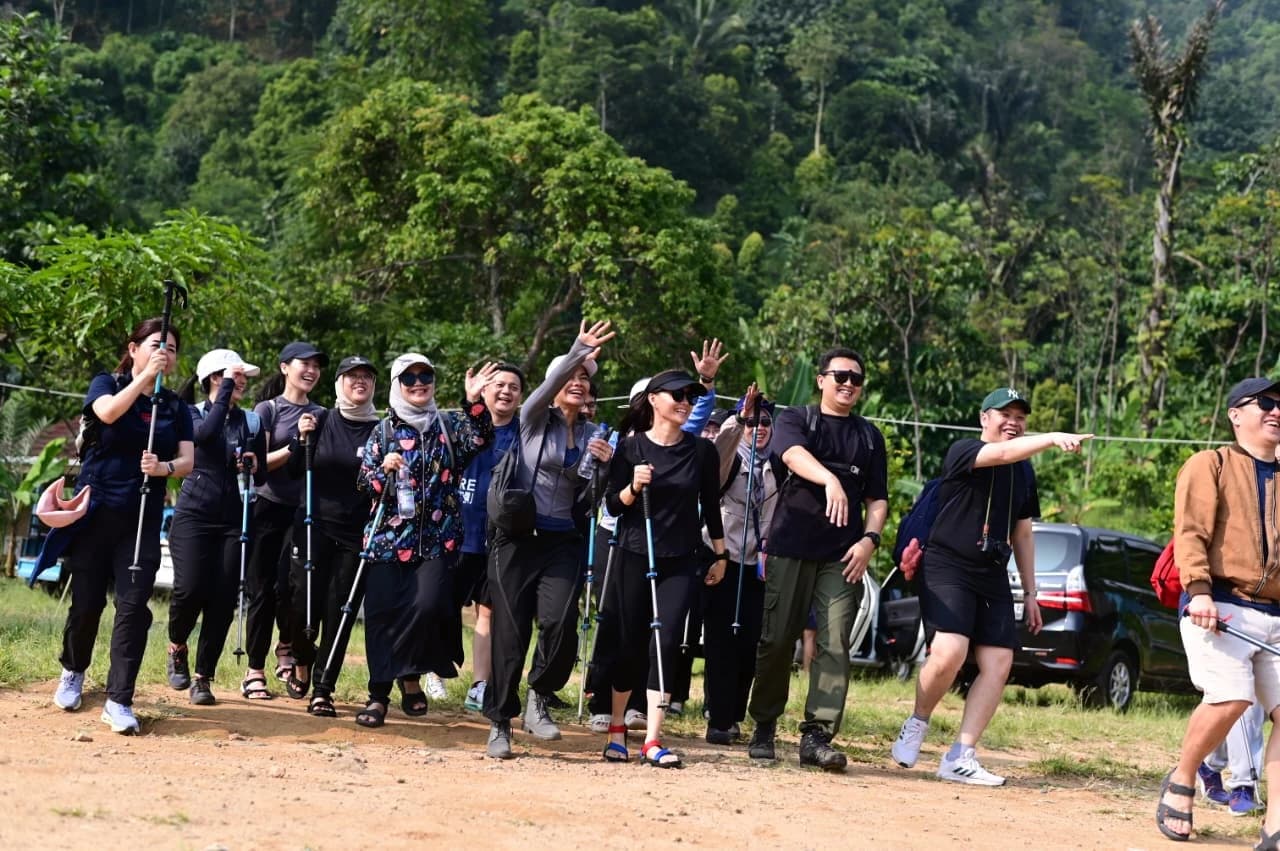 Seorang pemandu membantu peserta melewati jalur yang menantang di tengah hutan.