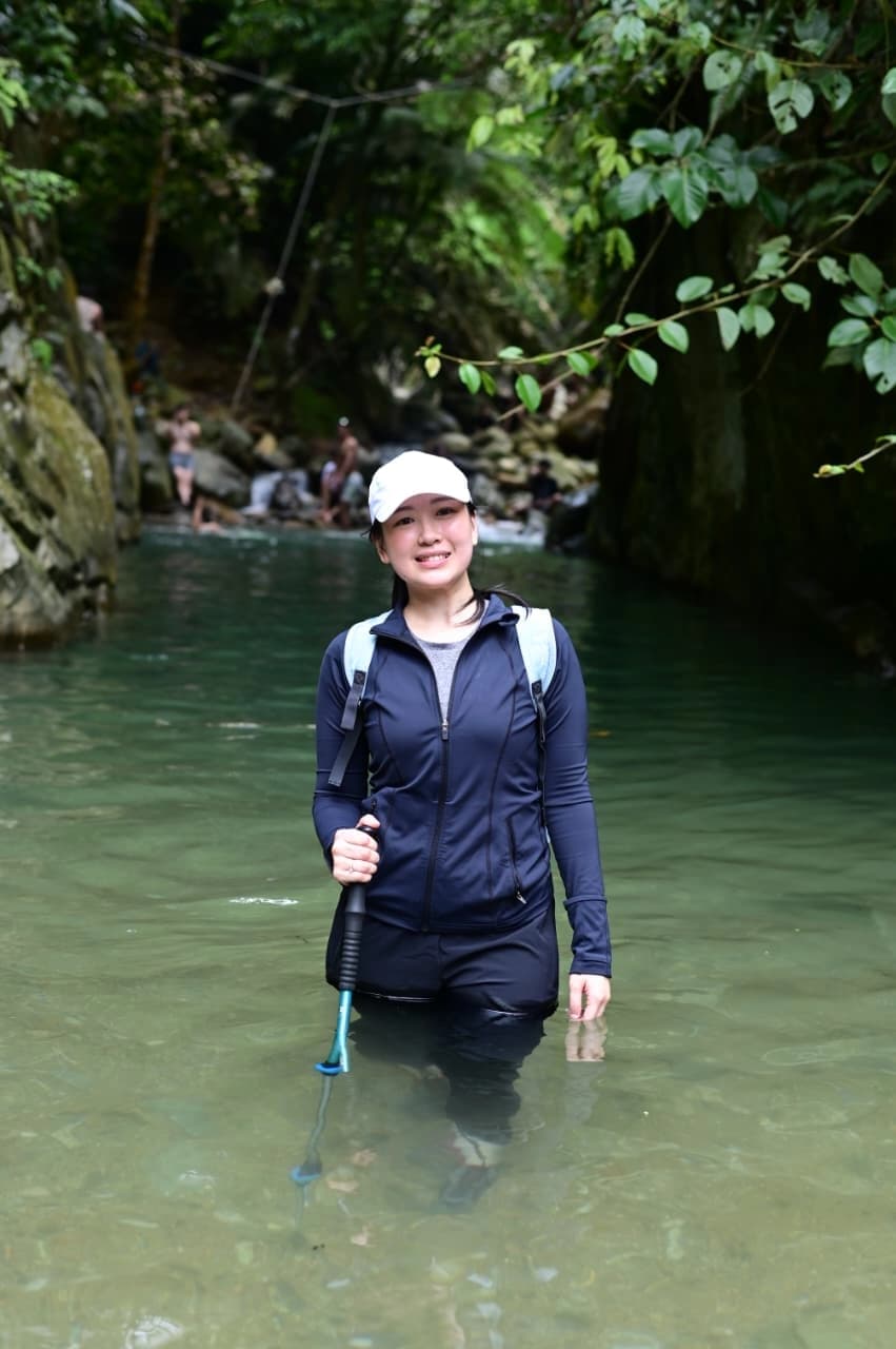 Seorang peserta pria berenang di kolam alami menuju air terjun yang dikelilingi tebing.