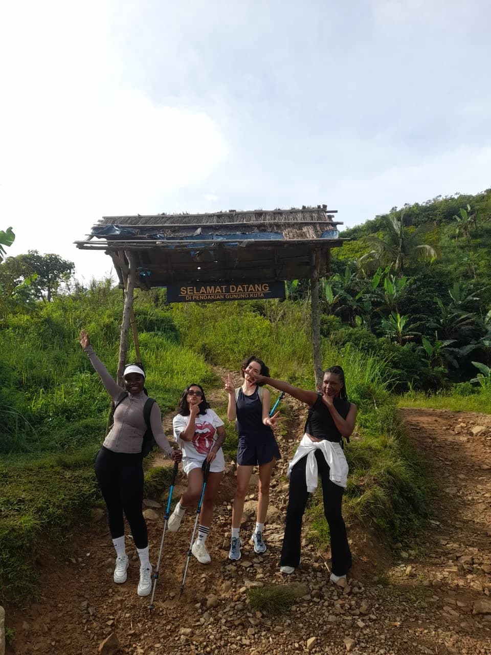 Rombongan trekking berpose di puncak bukit dengan pemandangan pegunungan yang menakjubkan.