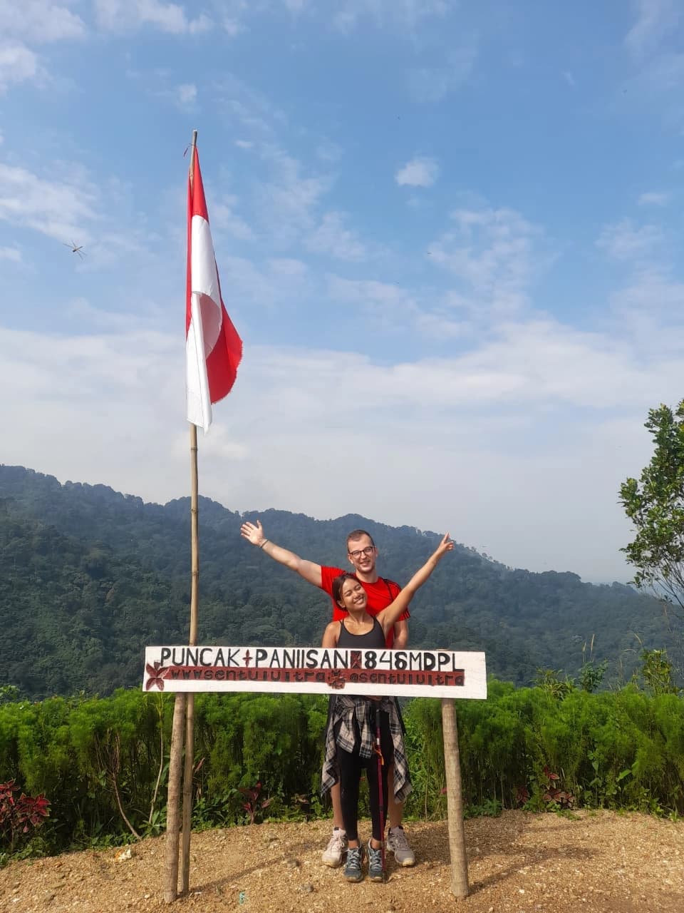 Sebuah keluarga kecil berpose di depan air terjun bertingkat yang indah.