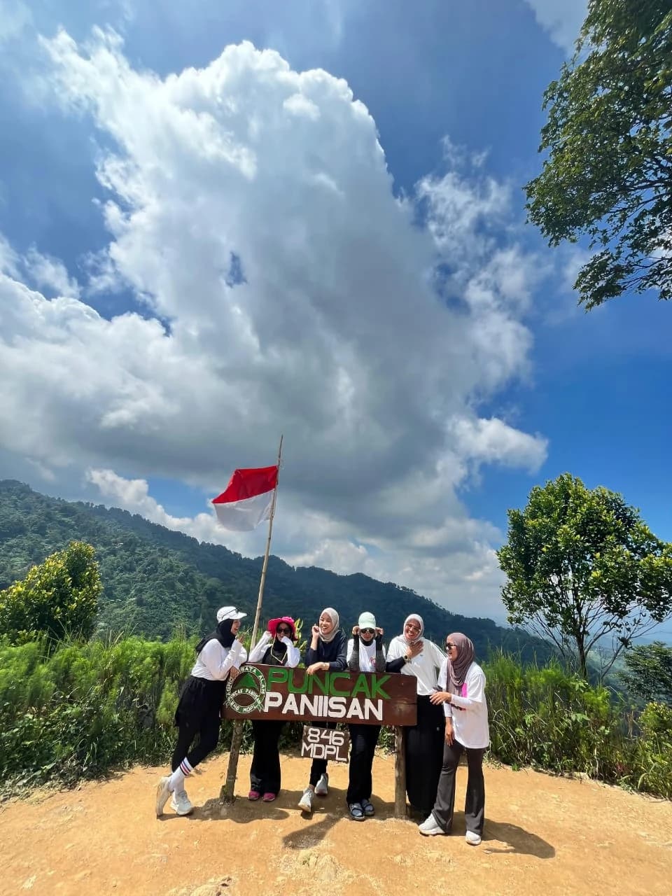 Sepasang pendaki merayakan pencapaian di titik pandang dengan pemandangan lembah.