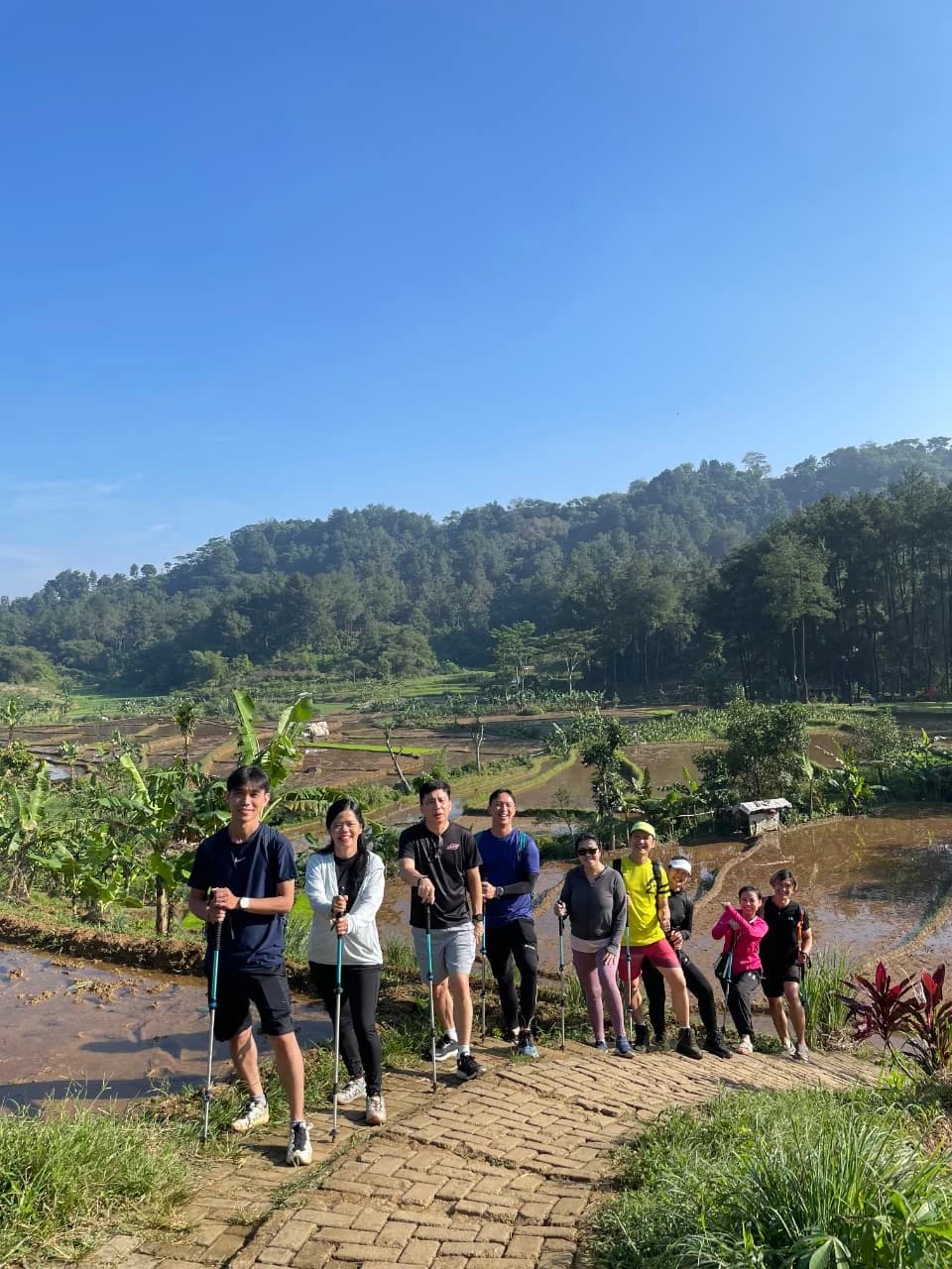 Peserta berpose di atas batu di tengah aliran sungai yang jernih.