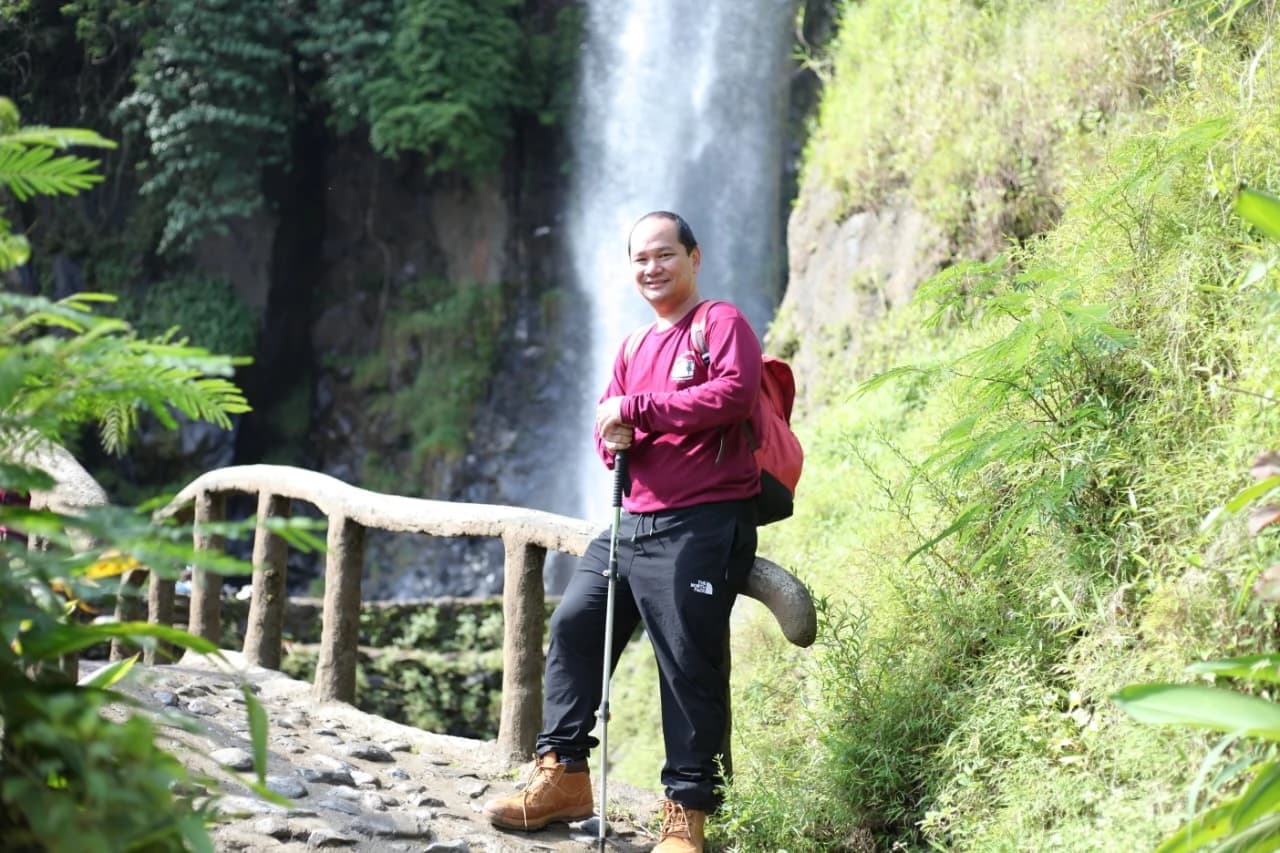 Peserta outing berpose untuk foto grup di bebatuan dekat curug.