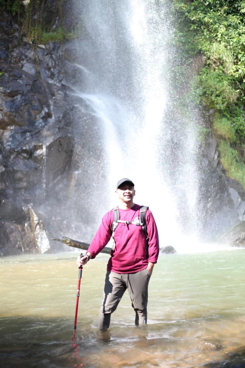 Seorang pemandu membantu peserta wanita saat melintasi sungai yang dangkal.