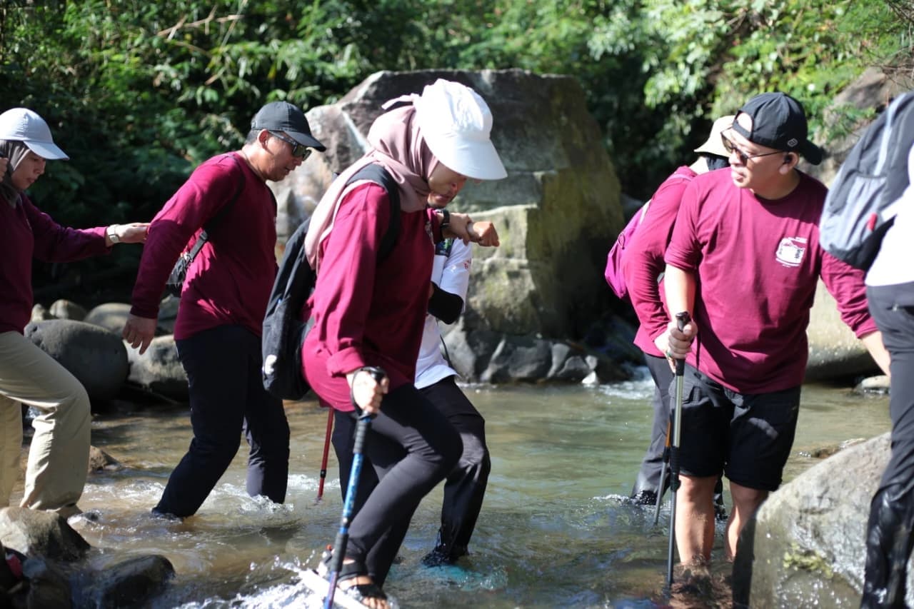 Para peserta wanita berjalan di jalur setapak saat mendaki bukit.