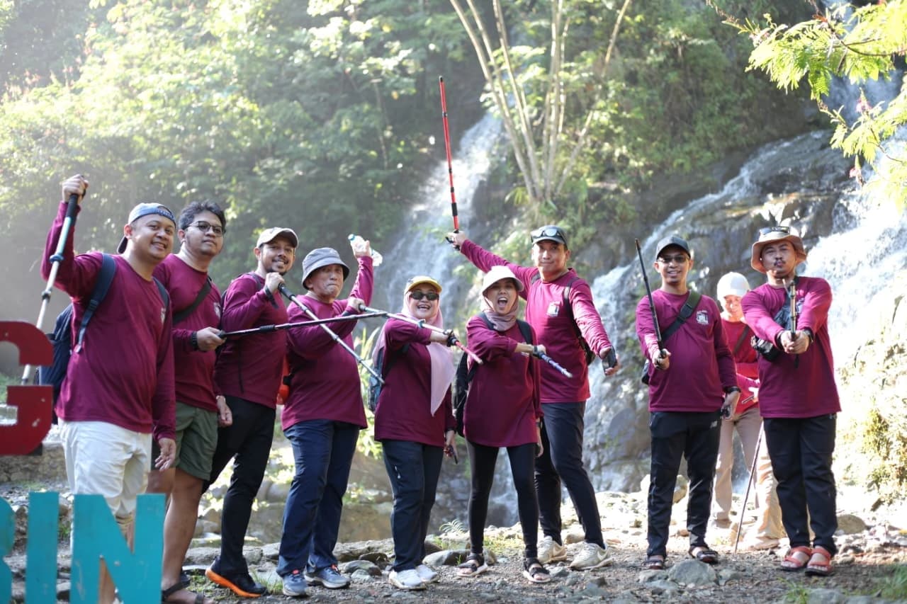 Rombongan peserta trekking saat melintasi jembatan besi berwarna biru.