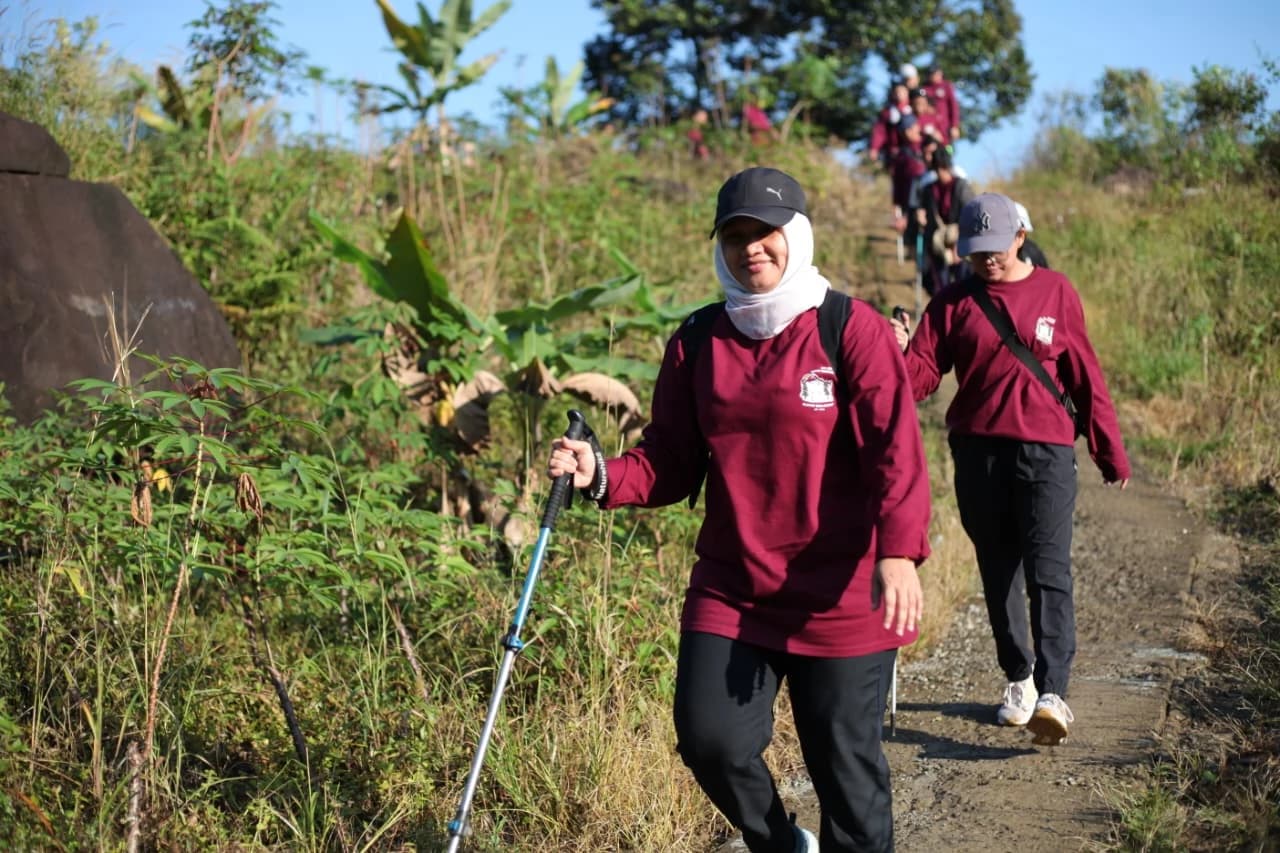 Peserta pria berdiri gagah di dalam air dengan latar belakang curug yang deras.