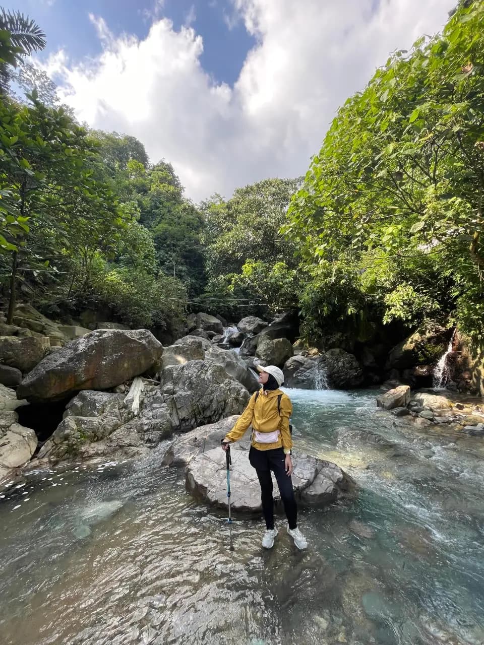 Rombongan peserta trekking berjalan di pematang sawah dengan latar langit biru cerah.