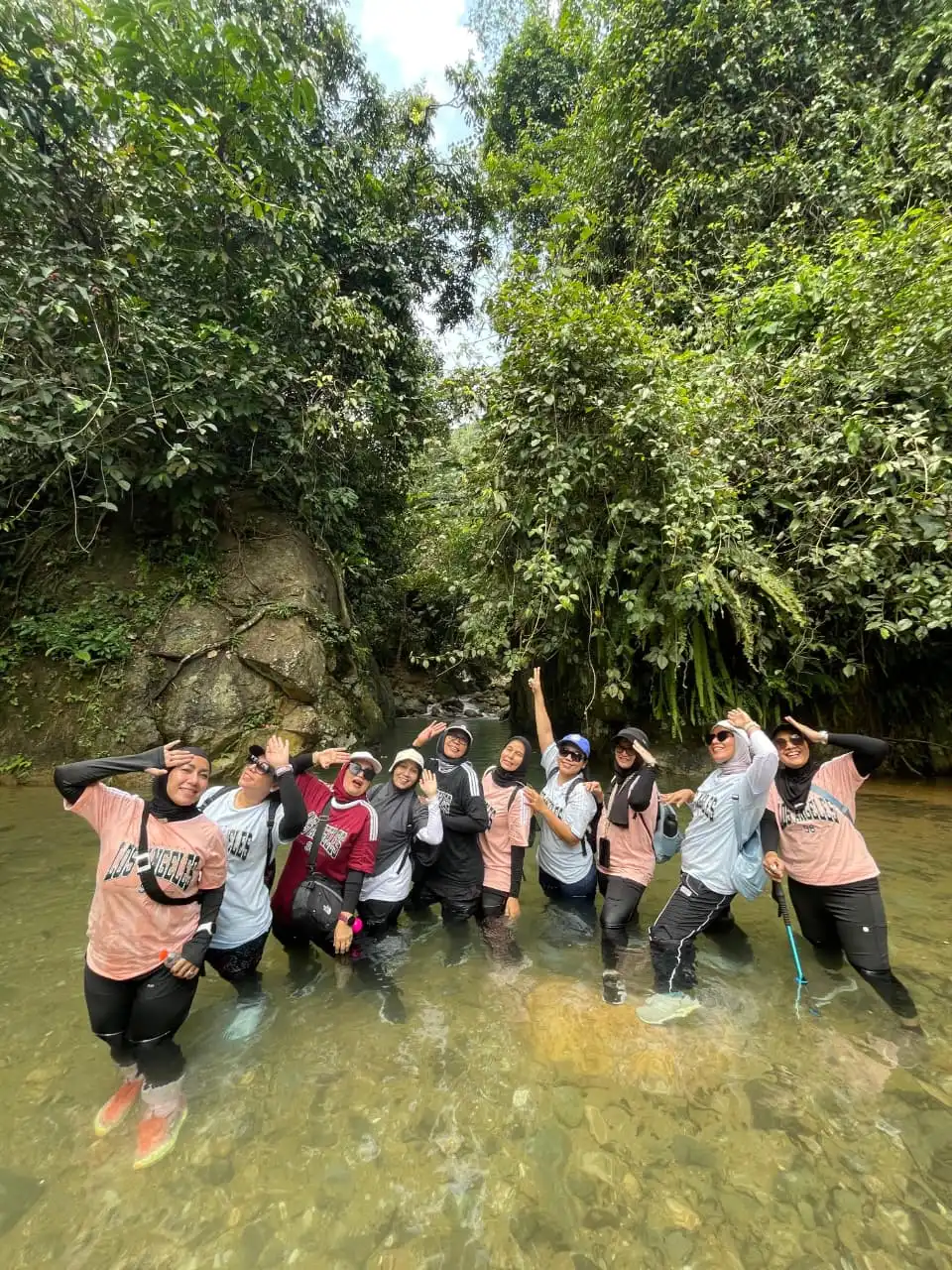 Grup peserta wanita berpose dengan gaya unik saat berdiri di aliran sungai yang dangkal.