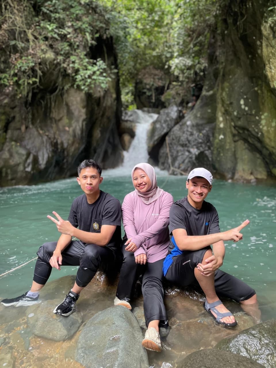 Peserta berpose di atas batu di tengah aliran sungai yang jernih.