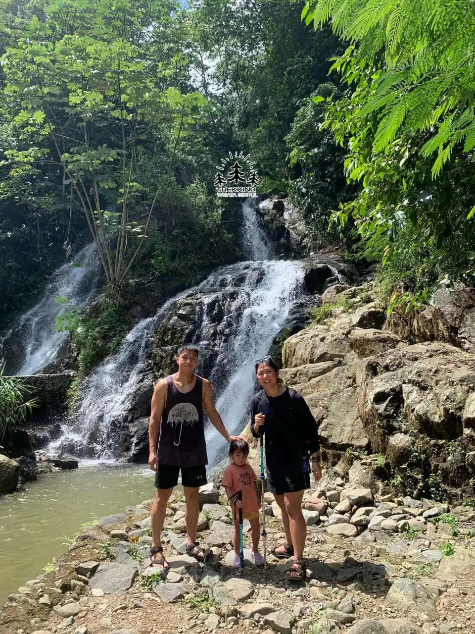 Seorang peserta merayakan keberhasilan mencapai curug yang diapit oleh tebing tinggi.