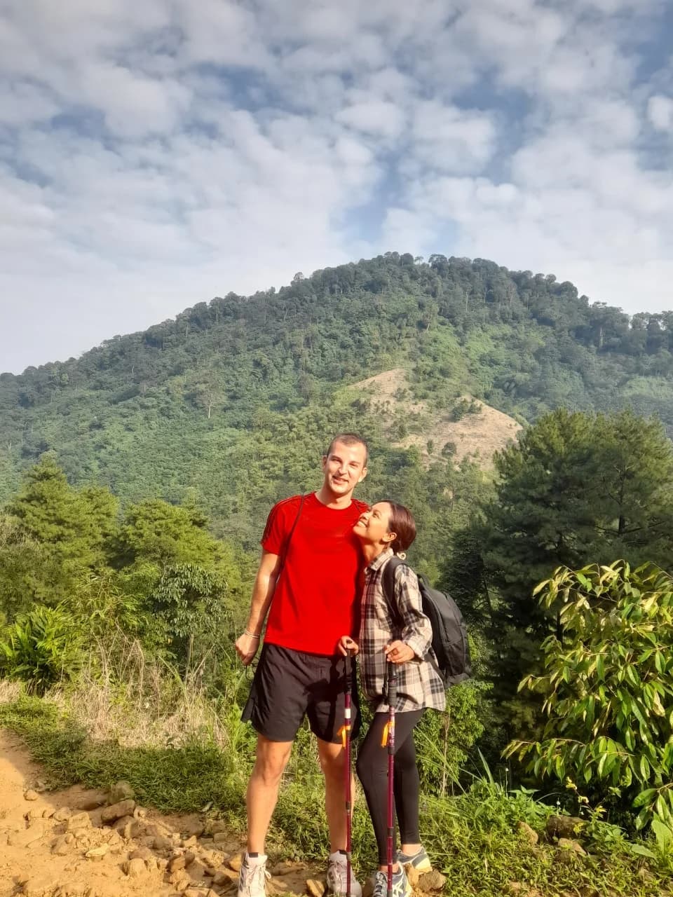 Sepasang pendaki merentangkan tangan di belakang papan penanda Puncak Panisan.
