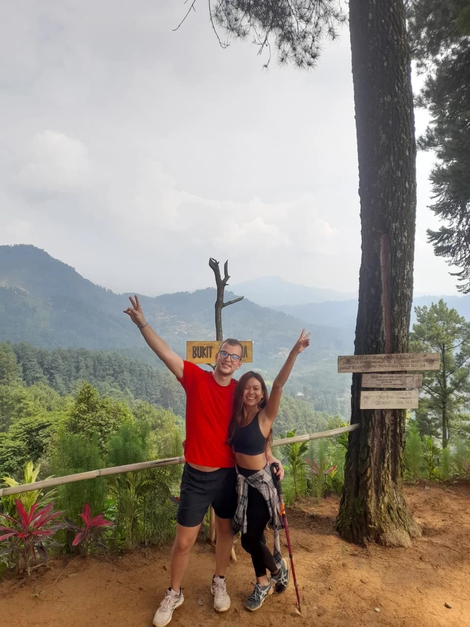 Seorang peserta merayakan keberhasilan mencapai curug yang diapit oleh tebing tinggi.