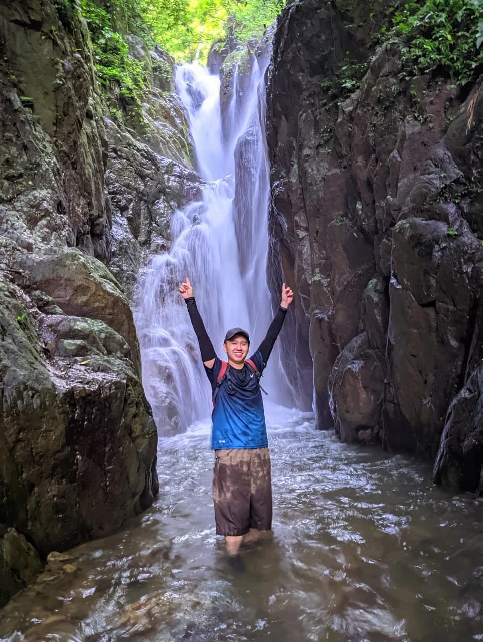 Pasangan pendaki berpose santai di papan penanda Puncak Panisan.