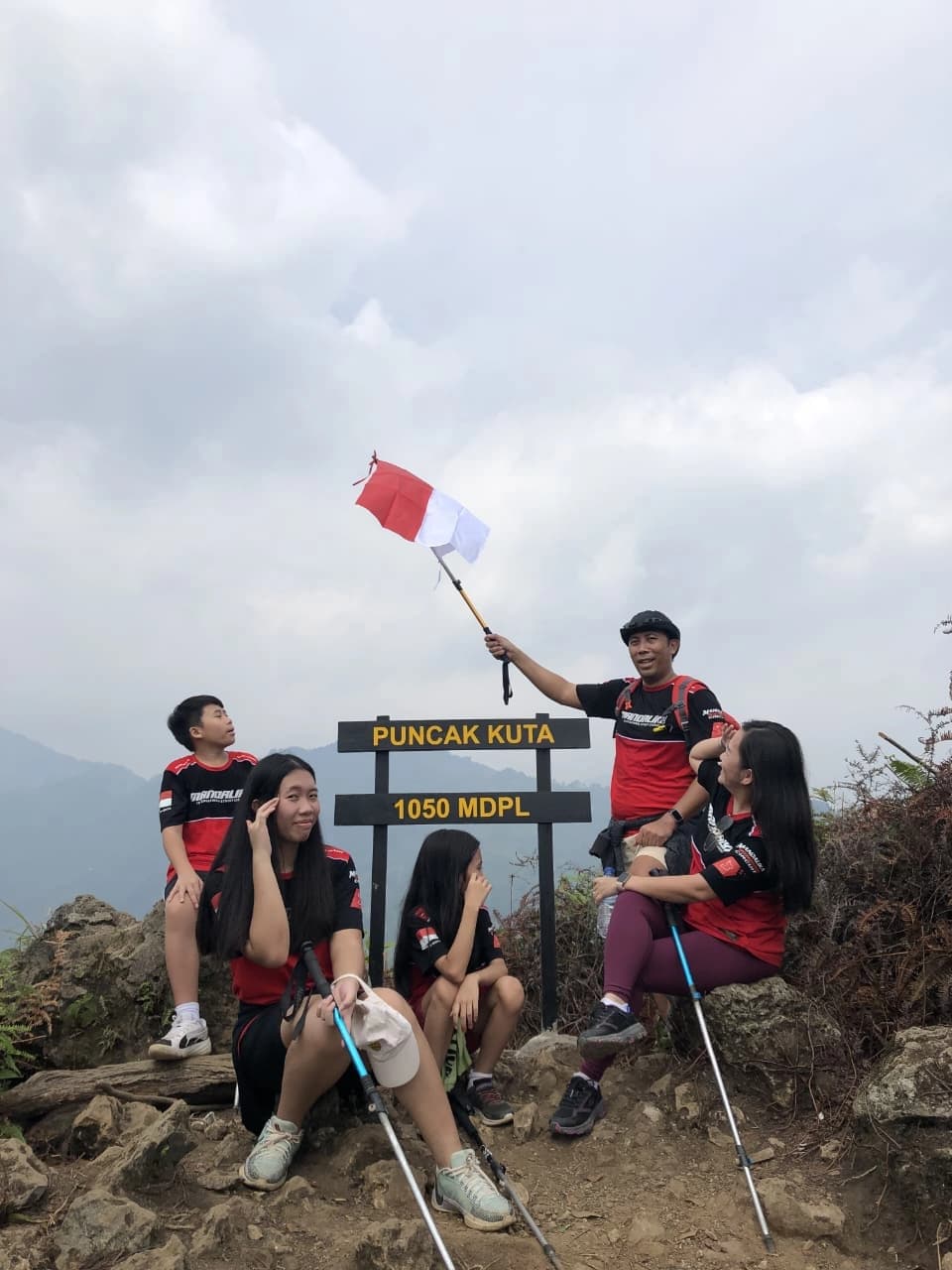 Sebuah keluarga berfoto di papan penanda Puncak Kuta 1050 MDPL.